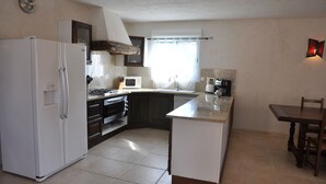 Eine kleine Küche mit Kühlschrank, Mikrowelle, Spüle und Esstisch.