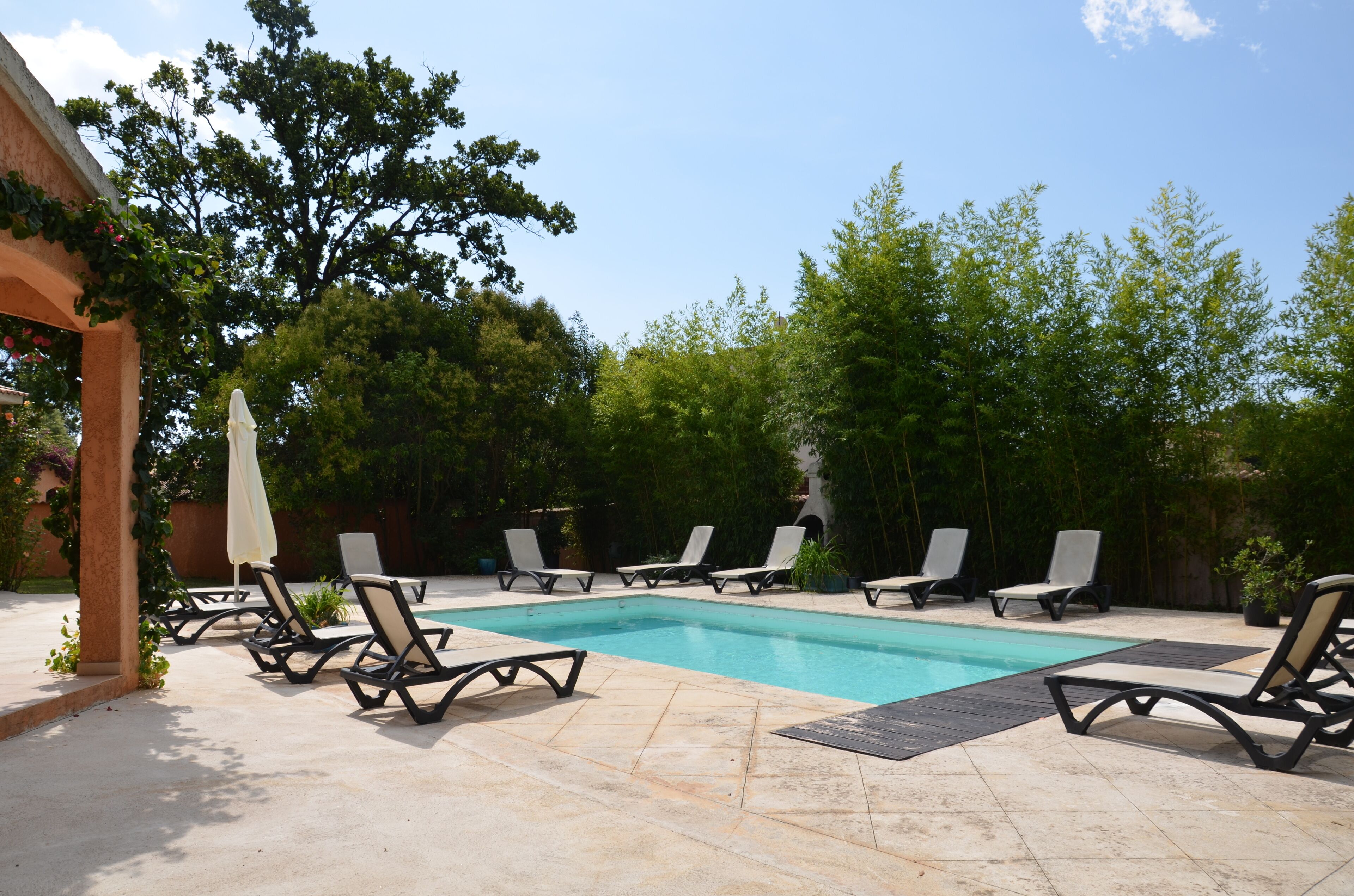 A swimming pool with lounge chairs and a pergola.