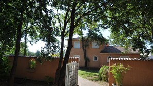 Ein Haus mit gepflasterter Auffahrt, einem umzäunten Bereich und einem Blumentopf.