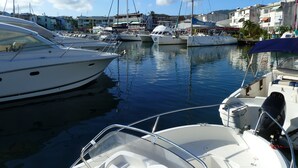 A marina with several boats docked, surrounded by buildings and palm trees.