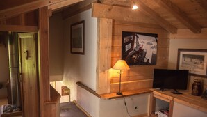 Un interior de madera con televisor, lámpara y cuadros en la pared.