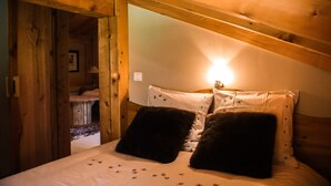 Acogedor dormitorio de cabaña de madera con cama, almohadas y mesita de noche.