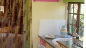 Una cocina con un lavamanos, una ventana y una celosía de bambú.