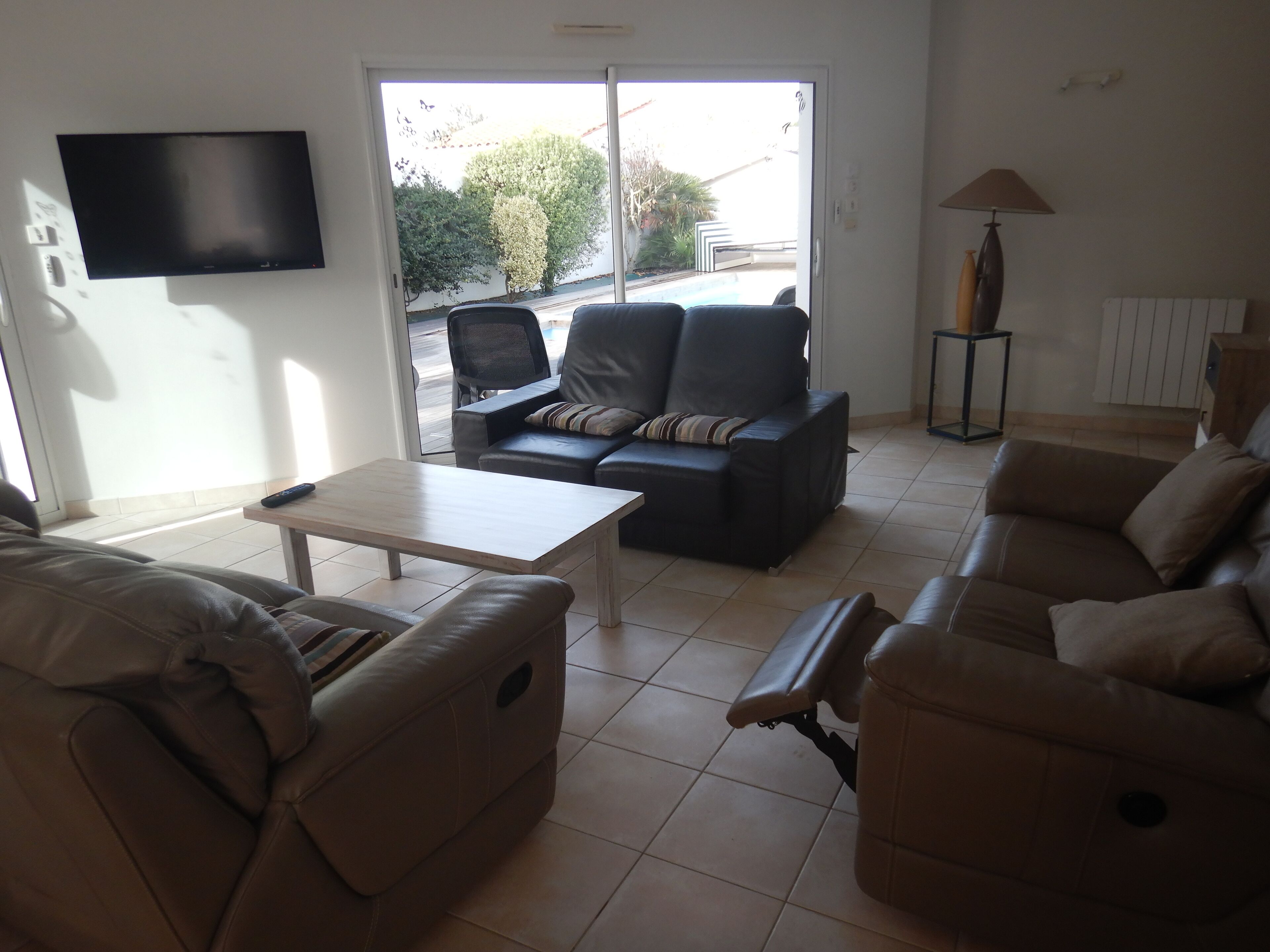 Una sala de estar con un sofá, una mesa de centro y un televisor montado en la pared.