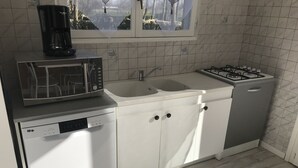 Cozinha com armários brancos, micro-ondas, lava-louças, pia e fogão a gás.