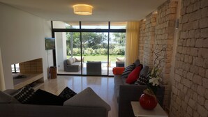 Uma sala de estar moderna com um sofá cinzento, uma mesinha com um vaso e uma parede de pedra.