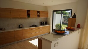 Cozinha moderna com armários de madeira, bancada branca e janela com vista para o exterior.