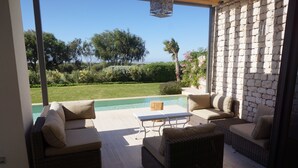 Um pátio com móveis de vime, piscina e muro de pedra.