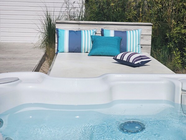 Un jacuzzi con cubierta de madera y pared blanca al fondo.