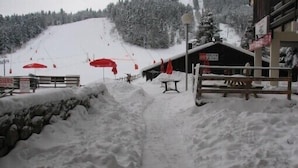 A snow-covered path leading to a building with a ski lift in the background.