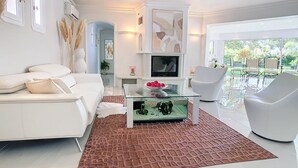 Una sala moderna con un sofá blanco, una mesa de centro de cristal y una chimenea.