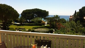 A balcony with a table, chairs, and a view of the sea and garden. - Apartment, facing the sea, near the beach, 6 people, 2 bedrooms (Le Lavandou)