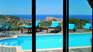 A poolside area with lounge chairs and a view of the sea.