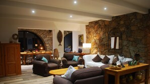 A cozy living room with a stone wall, a fireplace, and a dining area with wooden furniture.