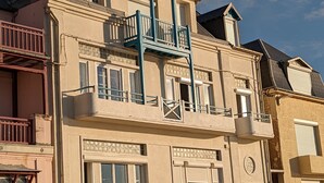 Un edifici de diverses plantes amb un balcó, grans finestres i un disseny de teulada característic.