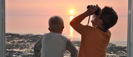 Twee mensen kijken naar een zonsondergang door een raam.