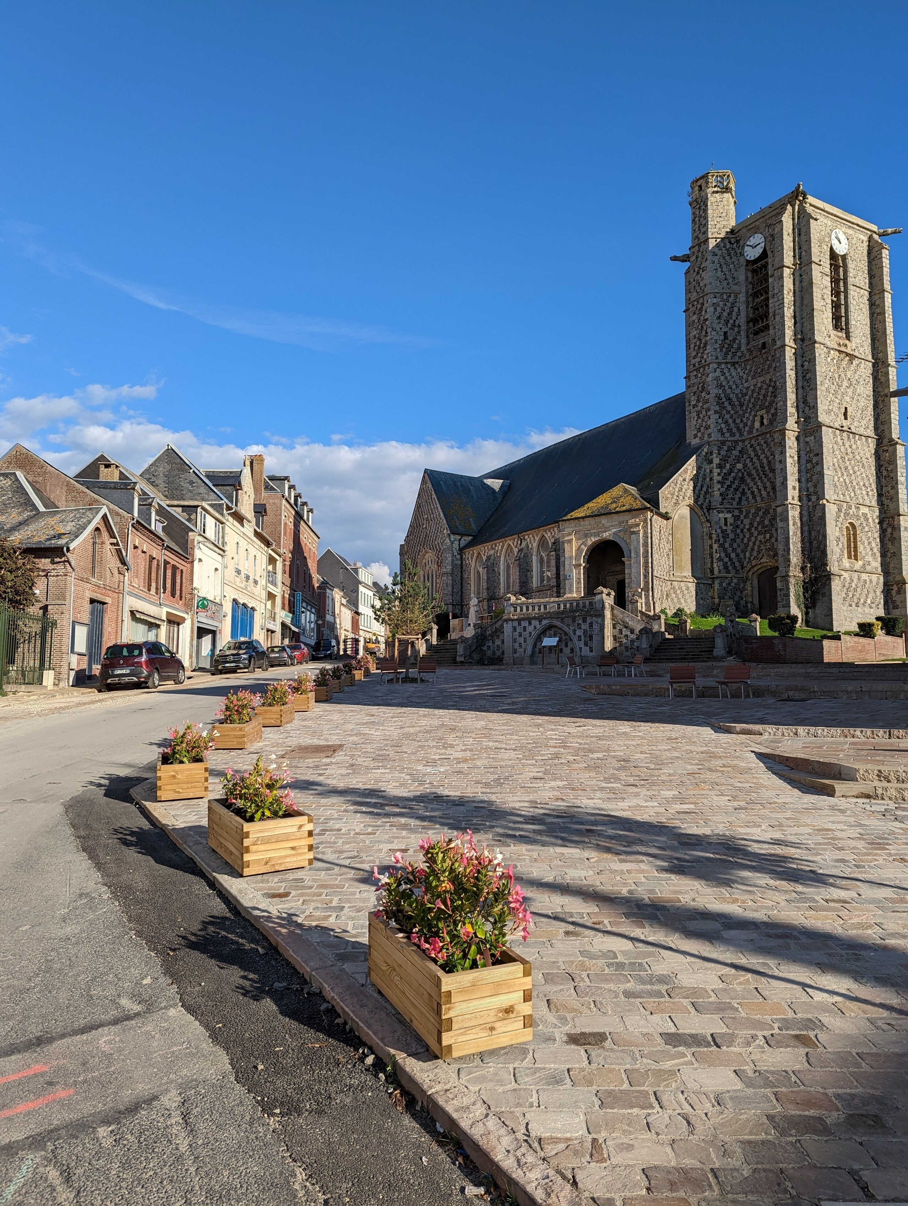 A historic town square with cobblestone pavement, a prominent church with a tall tower, and traditional buildings.