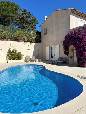 A swimming pool with a curved edge, surrounded by lounge chairs and a building with a tiled roof. - Villa located in Cagnes-sur-Mer, Cote d’Azur. For 8 people, with a swimming pool (Cagnes-Sur-Mer)