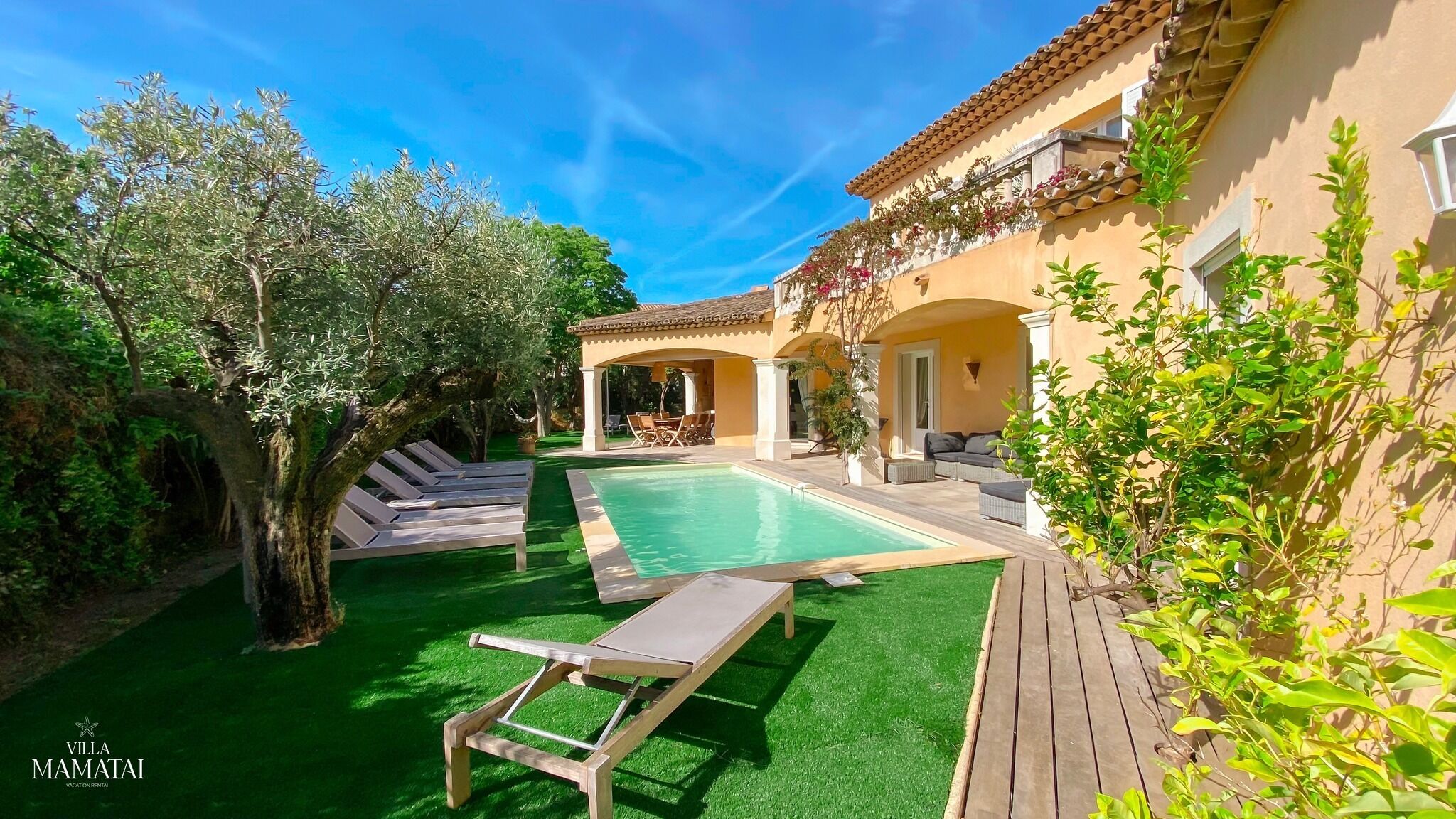 Een villa met zwembad, terras en tuin.