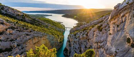 A gorge with a river, rocky cliffs, and greenery.