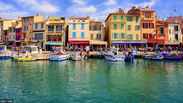 Une promenade en bord de mer, avec des bâtiments aux couleurs vives et des bateaux amarrés.