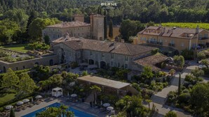 Un vaste domaine comprenant plusieurs bâtiments, une piscine et une végétation luxuriante.