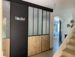 Ein moderner Empfangsbereich mit einem 'Welcome'-Schild, einer Schiebetür mit Milchglasfüllungen und einer Treppe zu einer weiteren Ebene.