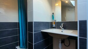 Une salle de bain moderne avec un lavabo, un miroir et un espace douche.
