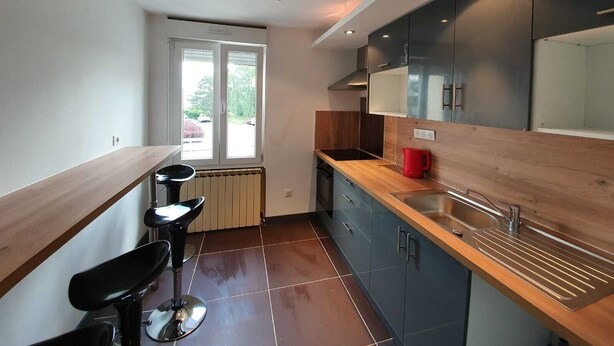 Une cuisine moderne dotée d’un plan de travail en bois, d’un évier encastré et d’une fenêtre donnant sur l’extérieur.