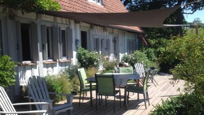 Ett trädäck med utemöbler, en täckt uteplats och ett hus med ett rött tegeltak.