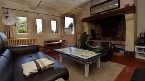 Ett vardagsrum med en öppen spis, en soffa, ett soffbord och en bokhylla.