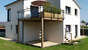 Une maison moderne à deux étages, dotée d’un balcon, d’un escalier et d’un petit jardin.