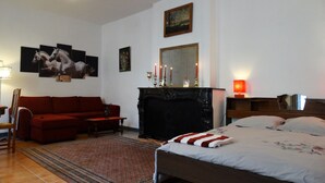 Un dormitorio con cama, sofá rojo, chimenea y decoración en la pared.