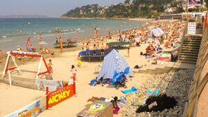 Ein überfüllter Strand mit einem Volleyballnetz, einem Trampolin und einem Rettungsturm.
