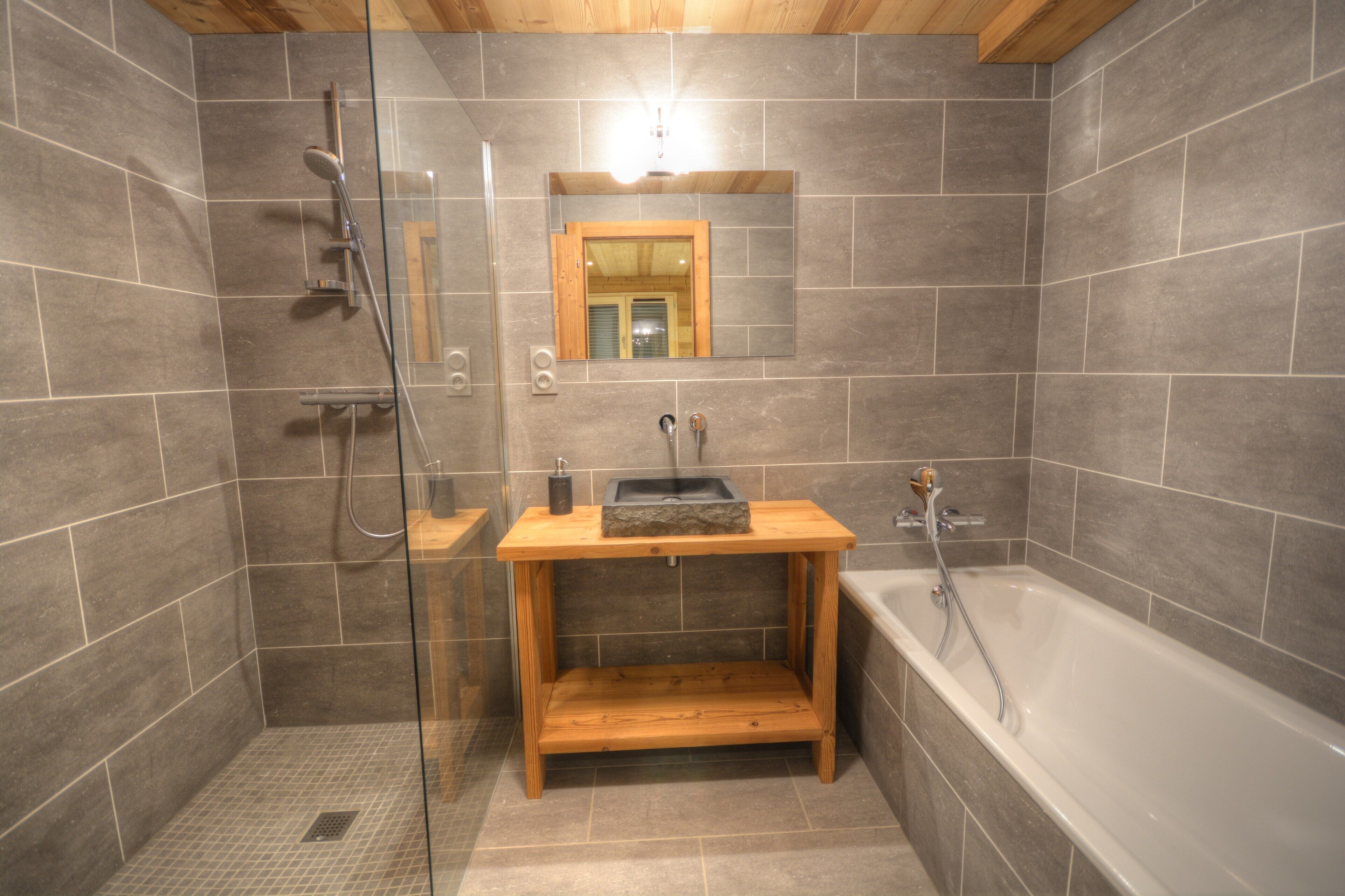 Ein modernes Badezimmer mit einer einteiligen Duschkabine, einem Holzbadezimmer-Waschtisch und einer freistehenden Badewanne.