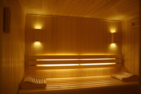 A sauna with wooden benches and built-in lighting.
