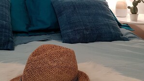 A bedroom with a bed, pillows, a hat, a lamp, and a cactus on a nightstand. - Resa 2025 open! SUPERB SEA VIEW mini villa heated pool Serra di Ferro (Serra-Di-Ferro)