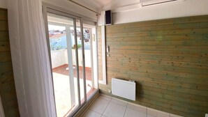 A room with a sliding glass door leading to a balcony, a white radiator, and a ceiling fan. - Cozy T2 Apt, 5 Guests, Terrace, Near Beach, Port Leucate (Port Leucate)