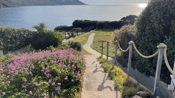 Un sentiero che conduce a un corso d'acqua con vista su colline lontane.