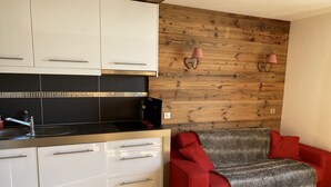 A compact kitchen with white cabinets, a black countertop, and a wooden accent wall.