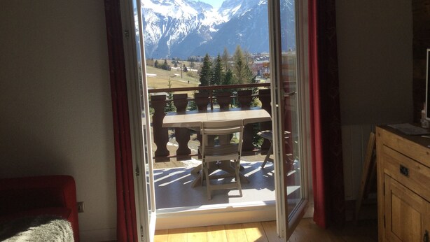 A room with a sliding glass door leading to a balcony with a mountain view.