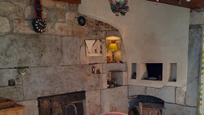 A rustic dining area with a stone wall, a fireplace, and a yellow tablecloth. - rental in the countryside in a quiet location   (Foncine-Le-Haut)