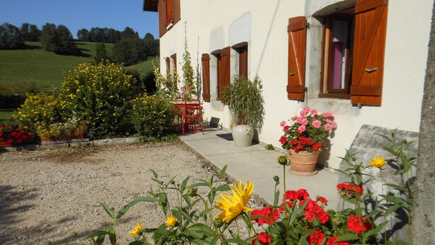 A white building with wooden shutters, surrounded by a garden with various flowers and plants. - rental in the countryside in a quiet location   (Foncine-Le-Haut)