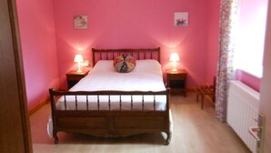 A bedroom with pink walls, a wooden bed, two bedside tables with lamps, and a window with a floral curtain. - rental in the countryside in a quiet location   (Foncine-Le-Haut)