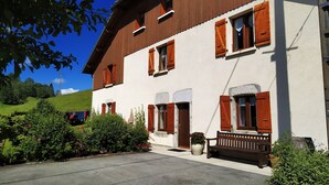 A two-story building with wooden shutters, a bench, and potted plants. - rental in the countryside in a quiet location   (Foncine-Le-Haut)