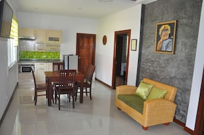 A modern kitchen with a dining area, a sofa, and a framed picture on the wall.