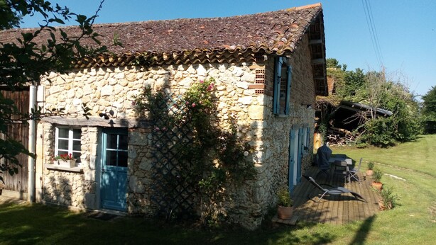 Una casa de piedra con tejado de baldosas, puerta de madera y una pequeña ventana.