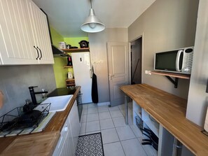 Eine kleine Küche mit Spüle, Arbeitsplatte, Mikrowelle und einer Pendelleuchte.