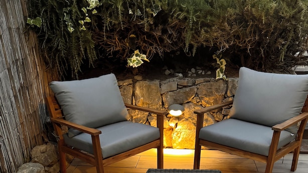 A wooden outdoor seating area with two chairs and a small table, set against a stone wall and a wooden floor. - Cute house with pool in picturesque village of the Massif des Maures (Collobrières)