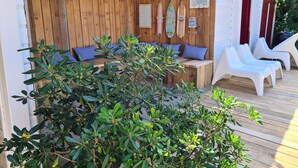 Um deck de madeira com mesa e cadeiras, rodeado por vegetação.